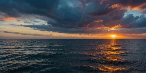 Fototapeta premium A serene ocean scene as the sunrise breaks through dramatic clouds casting a spectrum of colors reflected in the water.