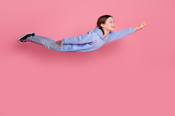 Full size photo of lovely small schoolkid raise fist fly empty space wear hoodie isolated on pink color background
