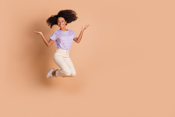 Full length portrait of pretty young woman jump hold empty space wear t-shirt isolated on beige color background