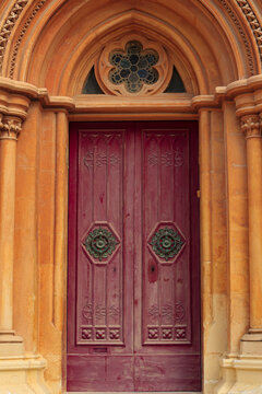Mdina, Malta. Limestone arches, Corinthian columns, rosette gothic stained glass and a red door