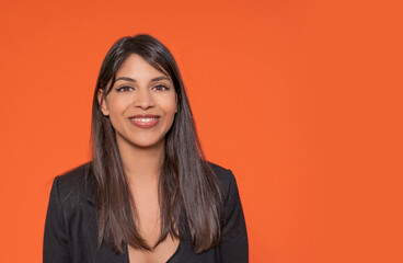 Obraz premium Professional Woman Smiling Against a Vibrant Orange Background in a Studio Setting
