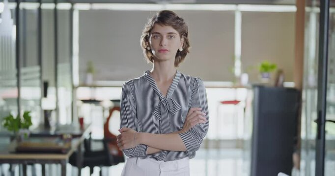 Young adult gen z cute girl agent boss standing proud fold hand look cam indoor job office happy french woman lady worker expert staff in formal dress cross arms do pose head shot video day work place