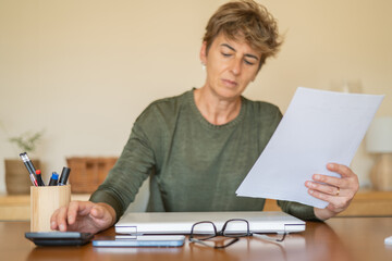 Business, summarize household expenses, manage budget, accounting concept. Mature woman use...