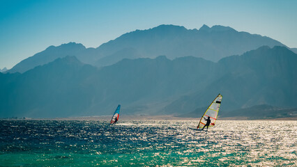 surfers ride in the sea on the background of the rocky coast in Egypt Dahab