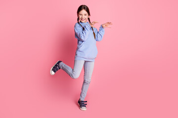 Full size photo of lovely small schoolkid arms scare empty space wear hoodie isolated on pink color background