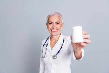 Portrait of aged woman professional doctor hold medication wear white coat isolated on grey color background