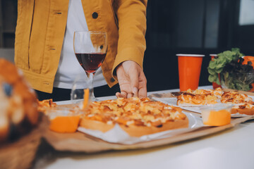 Happy friends making a toast with beer before eating pizza in a shared apartment.