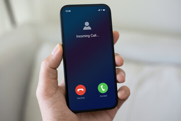 male hand holding phone incoming call on screen light room