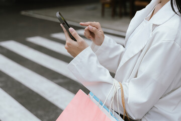 A young woman walks through the city, carrying shopping bags and talking on her mobile phone. She’s carefree and excited, embodying modern consumerism. The vibrant street reflects her joyful, fashiona