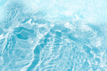Blue water with ripples on the surface. Defocus blurred transparent blue colored clear calm water surface texture with splashes and bubbles. Water waves with shining pattern texture background.