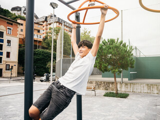 Young boy playing on monkey bars in an outdoor playground, smiling as he swings from one bar to another.