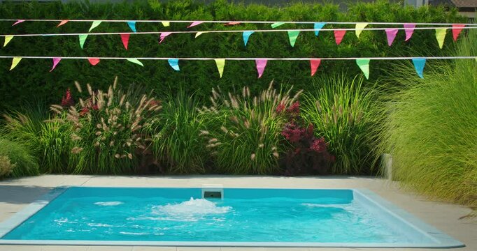 Empty pool with vibrant flags above, surrounded by lush greenery.
