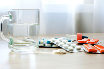 Glass with clean water and medicine pills on the table. Close-up, selective focus.