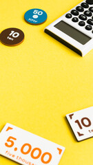 計算機とおもちゃのお金　家計　出費　支払い　会計　黄色背景