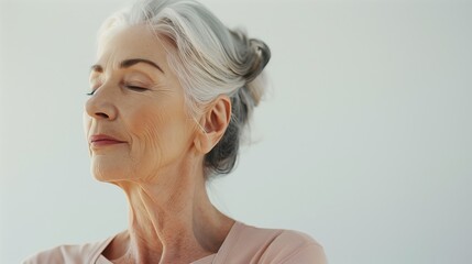 Portrait of a beautiful senior woman with grey hair breathing deeply in yoga clothes on white background