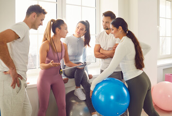 Team of athletes is communicating with instructor during a fitness training session in the gym. Group activity promotes teamwork and active participation in sports, enhancing overall fitness level.
