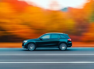 The car is driving on the road in an autumn forest, with a blurred background