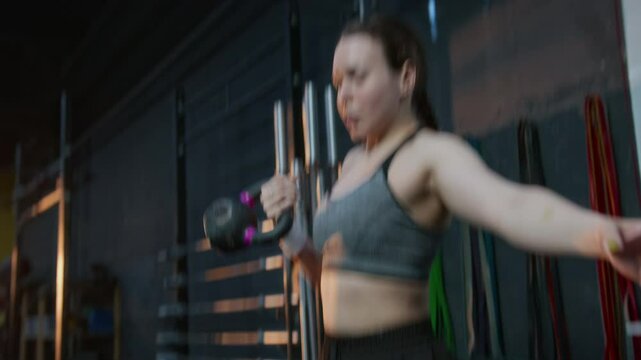 Fitness girl doing kettlebell hang power snatch during her cross functional workout in gym