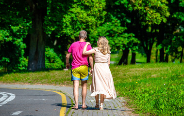 A man and a woman walk in a summer park
