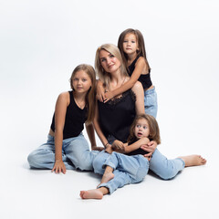 Group photo of a blonde mother with three adorables  daughters, lying on a floor, isolated on a white background.