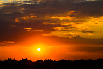 Sunset Sun in Cloudy Sky over City Rooftops