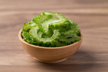 Sliced bitter gourd in bowl on wooden background, Food ingredient