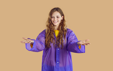 Woman with blue raincoat on light beige background, copy space.