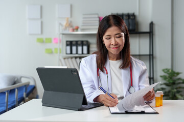 Young female doctor sitting at the desk preparing to receive patients in the medical clinic. Medicine. Data recording. Medical personnel at a clinic or hospital.