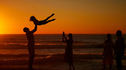 Family, generations and happy at beach for bonding on break, relax and fun in Spain. People, smile and playful on silhouette at ocean on holiday with happiness for travel, trip and adventure to chill