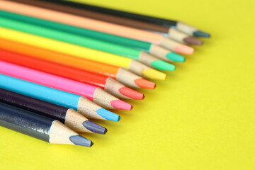 a group of multi-colored colorful large pencils on a yellow background