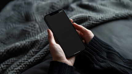 Close-up of a modern smartphone in hands on a gray plaid background. Black technology phone indoors. Concept of technology, modernity.