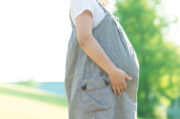 草原でお腹を抱える妊婦