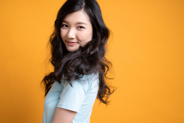 黄色のバックアップの前で立っている若い女性モデル