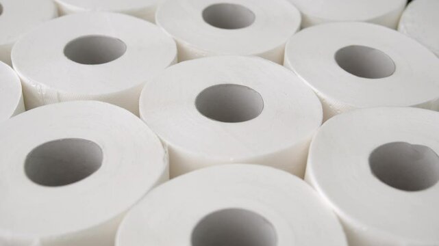 Close up on toilet paper rolls. Camera moves over many toilet paper rolls packed close to each other.