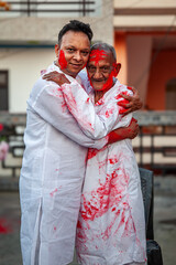 An Indian father and son joyfully celebrate the traditional festival of colors, Holi, by embracing each other, symbolizing love and tradition.