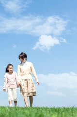 芝生を歩く母親と娘