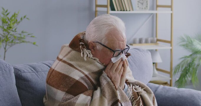 Old sick man, senior person feeling bad at home, poor health annoyed, worried aged pensioner measuring temperature. Sad grandfather in plaid sneezing and sickness or virus coughing, using handkerchief