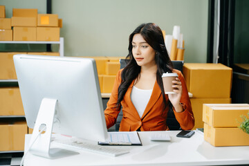 Young business owner woman prepare parcel box and standing check online orders for deliver to customer