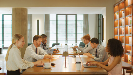 Multi-Cultural Business Team Seated At Desks Working On Laptops In Modern Office 