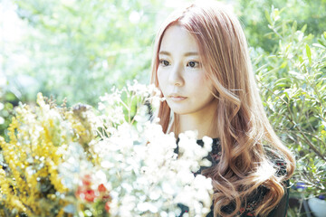 Naklejka premium 植物に囲まれて、ドライフラワーの花束を持つ女性のアップ写真
