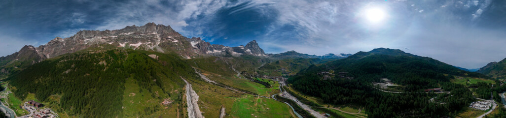 Obraz premium Aerial view of Mount Cervino, The Matterhorn, seen from Breuil-Cervinia. Green valleys and waterways that descend from the glaciers. Italy. Paths and trails in the Cervinia valley, refuges