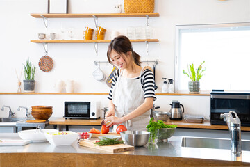 キッチンで料理を作る若い女性