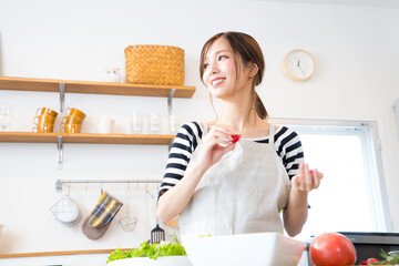 キッチンで料理を作る若い女性