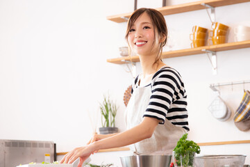 キッチンで料理を作る若い女性