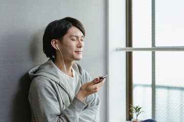 月額の音楽を楽しむ若い男性・サブスクやユーチューブ動画を見る