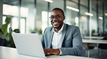 Fototapeta premium A happy Black businessman working on his laptop in an office.