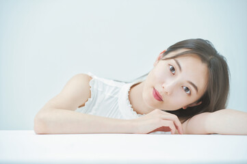 Obraz premium 白いテーブルにもたれかかるポーズをする若い女性