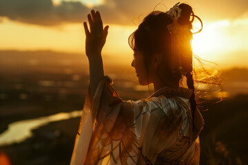 A woman in Chinese traditional dress waving. View over a scenic landscape with a winding river at sunset.