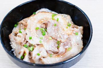 Donburi rice topped with chashu pork slices  in a black bowl.