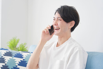 部屋でスマホを使う男性